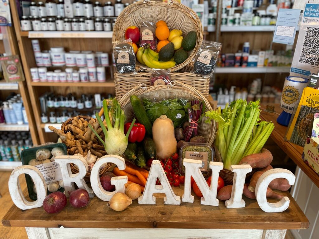 D2E image A table of organic fruit and vegetables on a table with wooden letters spelling 'organic' pictured inside Down to Earth organic food sellers in Midwest, Sussex.