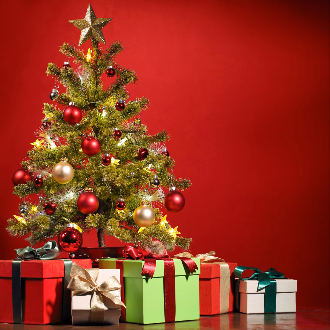 A decorated Christmas tree on a red background with five boxed and wrapped presents underneath.
