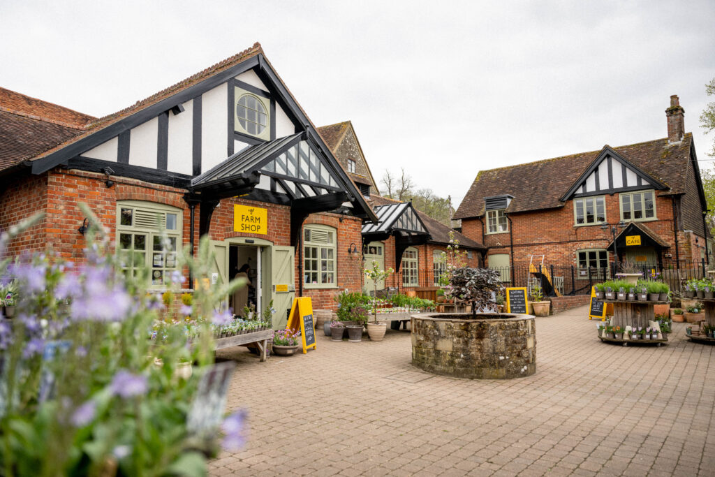 (c) Cowdray – 26-04-24MattAustin-232 The courtyard of Cowdray Farm Shop & Cafe in Midhurst filled with plants.