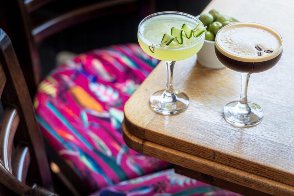 A closeup of two cocktails and bowl of olives on a table at The Swan Inn in Midhurst.